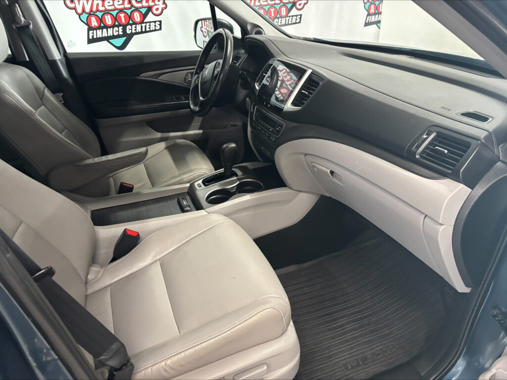 Interior of a car: beige leather front seats, center console with cupholders and gear shifter, steering wheel, and dashboard with a touchscreen.
