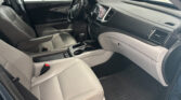Interior of a car: beige leather front seats, center console with cupholders and gear shifter, steering wheel, and dashboard with a touchscreen.