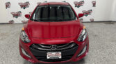Front view of a red Hyundai car parked indoors with a Wheel City Auto Finance Centers backdrop behind it.