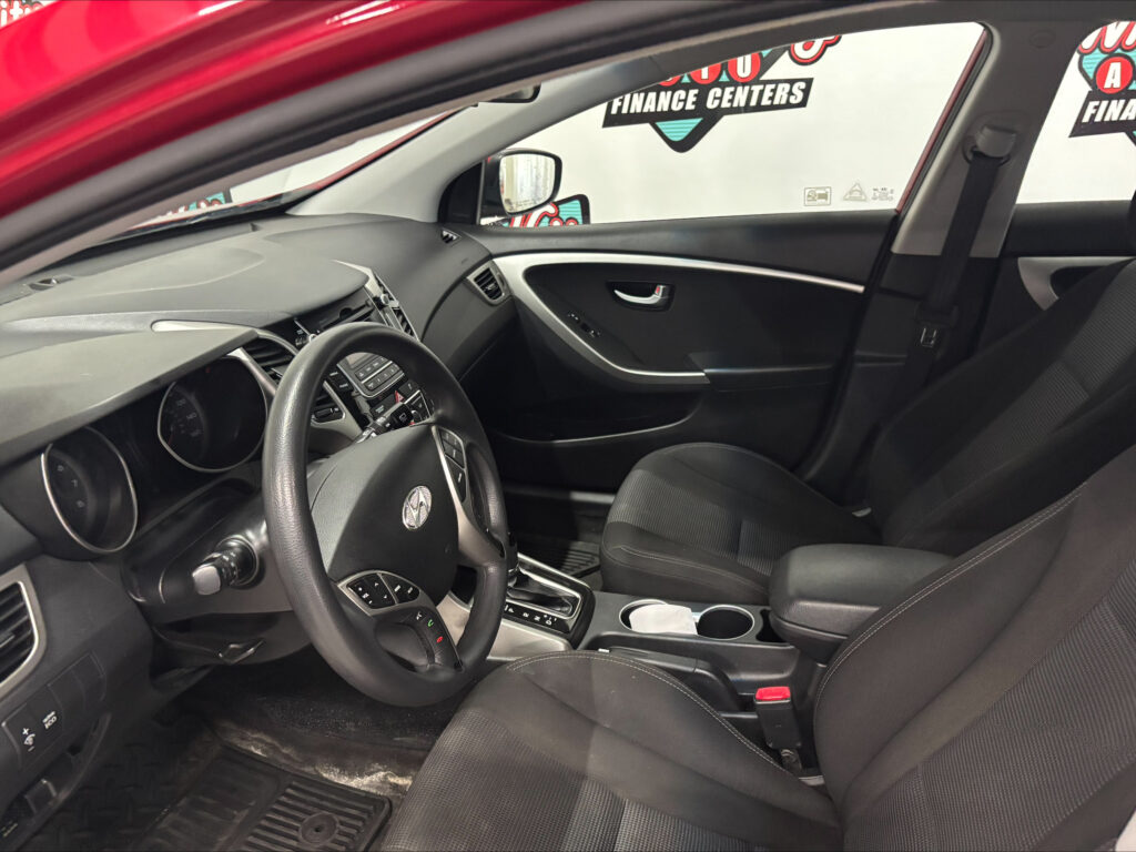 Interior of a car viewed from the driver's seat, showing steering wheel, dash, center console, and front passenger seat with seatbelt visible