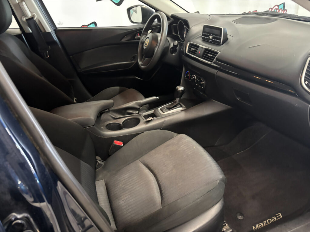 Interior of a Mazda car with black seats, steering wheel, center console, and dashboard visible.