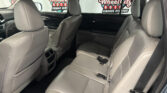 Back seat of a gray leather SUV interior, with rear doors open and a dealership sign visible through the windows outside: Wheel City Auto Finance Centers.