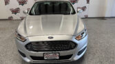 Front view of a silver Ford SUV in a showroom with Wheel City Auto Finance Centers backdrop logos behind it.