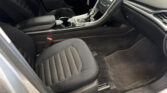 Front interior of a car showing the center console with gear shifter, cup holders, and black leather seats.