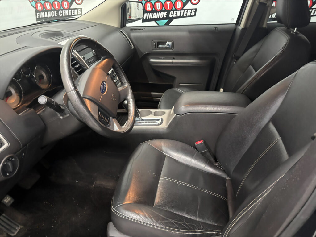 Inside a black leather car cockpit with steering wheel, center console, and front seats visible in the cabin