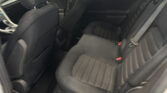 Back seat area of a dark car with black fabric upholstery, headrests, and red-seatbelt buckles visible on the right.