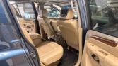 Beige leather SUV interior with rear door open, showing back seats and wood-trim door panel.