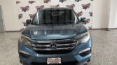Front view of a blue Honda SUV indoors at a dealership, with a Wheel City Auto Finance Centers backdrop behind it.