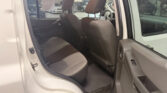 Open rear passenger door of a white SUV showing the gray fabric back seat and front seats in a showroom.