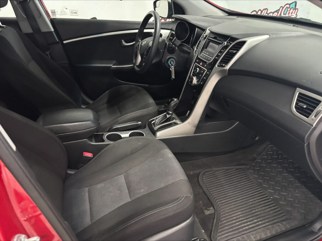 Interior of a car showing front seats, steering wheel, center console, and gear shifter inside a red exterior vehicle