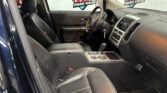 Interior of a black leather SUV showing steering wheel, gear shift, and center console; dealership banner visible through the windows with Wheel City Auto Finance Centers logos.