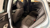 Open rear door shows the car's back seat area with black cloth seats and front seats visible inside a blue vehicle.