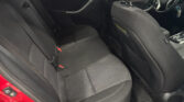 Rear and front seats in a dark fabric car interior with the steering wheel visible in the front right.
