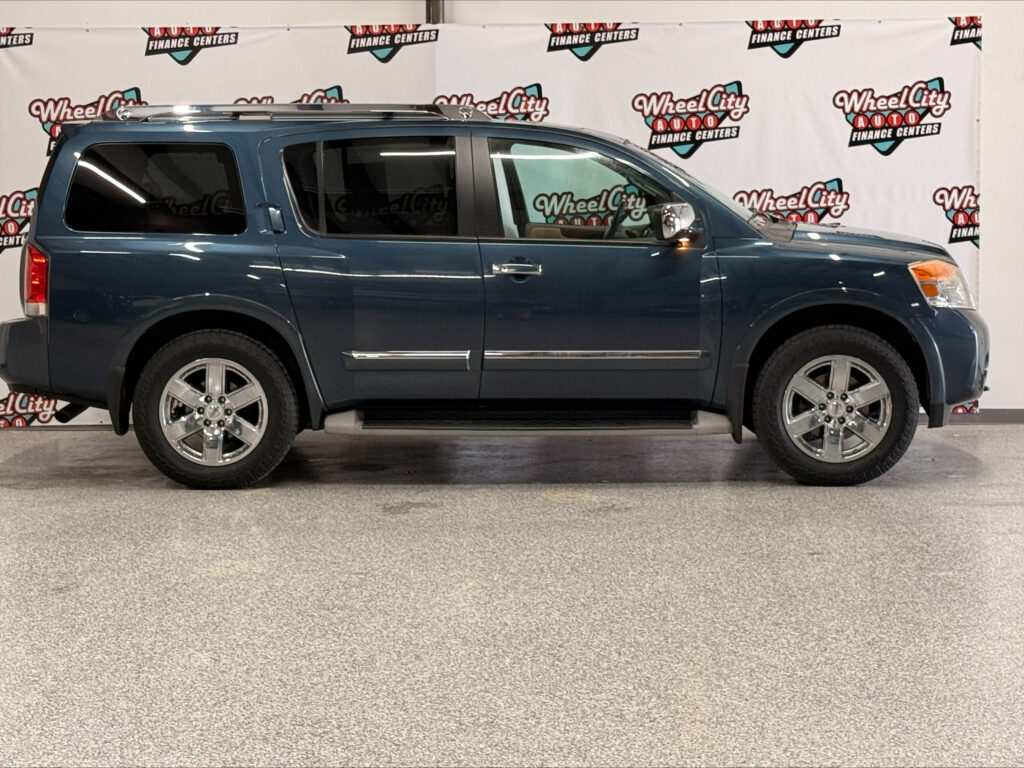 Blue SUV/minivan in a showroom with Wheel City banners in the background, side profile view.