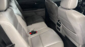 Back seat area of a gray leather car interior, with the driver and passenger seats in front and red seat belt buckles visible by the lower cushion.