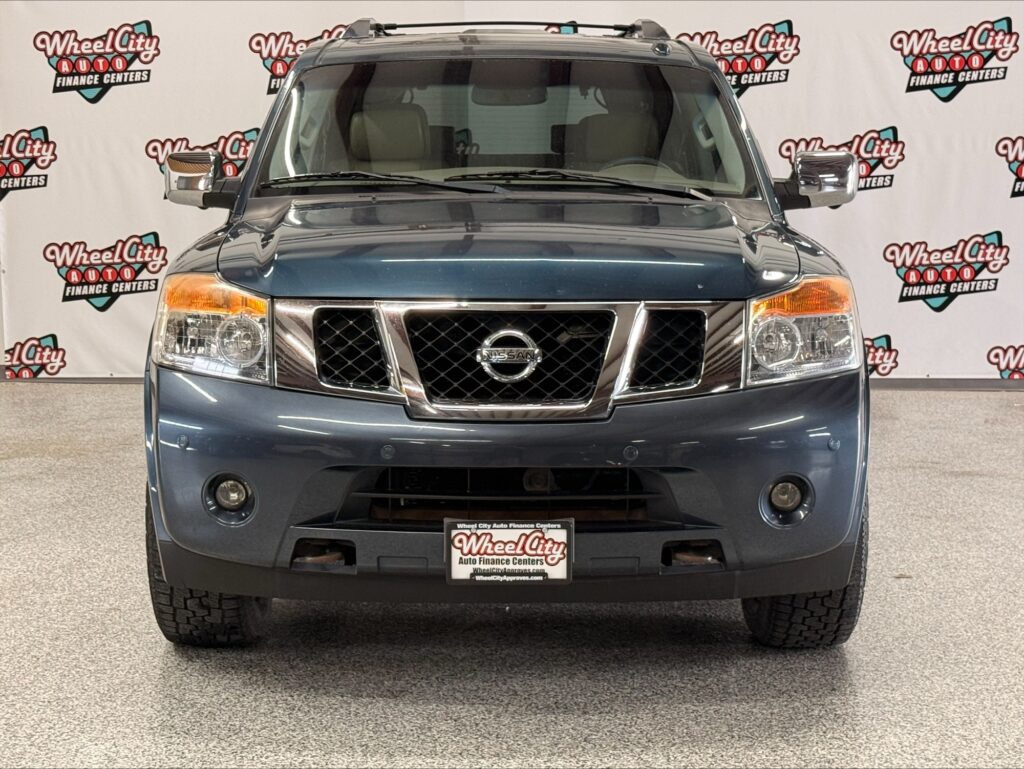 Front view of a blue Nissan SUV in a Wheel City Auto showroom backdrop