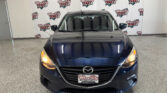 Front view of a dark blue Mazda parked indoors with a Wheel City Auto Finance Centers backdrop behind it
