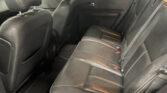 Back seat of a black leather car interior with visible headrests and seat belts, door panel in view.