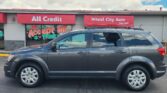 Storefront with red awnings reading 'All Credit' and 'Wheel City Auto Since 1993'; a gray SUV is parked in front.