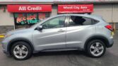 Silver SUV parked in front of a storefront with red All Credit and Wheel City Auto signs; car partially blocks the window display saying We Accept All Trade.