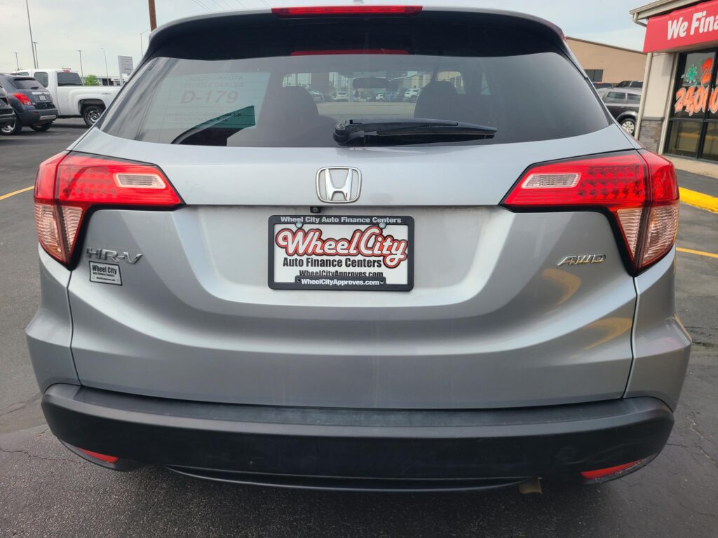 Rear view of a silver Honda SUV in a car lot, showing taillights, rear wiper, and Wheel City license plate frame on the bumper.