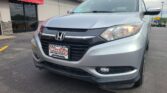 Silver Honda SUV parked at Wheel City Auto dealership under a red awning.