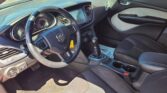 Interior of a car showing the steering wheel, dashboard, center touchscreen, gear shifter, and front seats in black fabric.