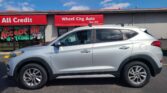 Silver SUV parked in front of Wheel City Auto dealership with red 'All Credit' and 'Since 1993' signs.