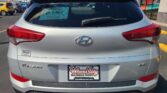 Rear view of a silver Hyundai Tucson in a car dealership lot with Wheel City license plate frame and Window sticker visible on the rear window.