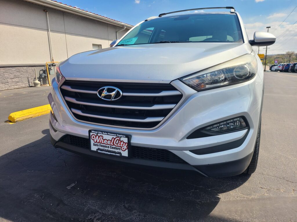 Front three-quarter view of a white Hyundai SUV in a parking lot, dealership plate visible reading Wheel City Auto Finance Centers