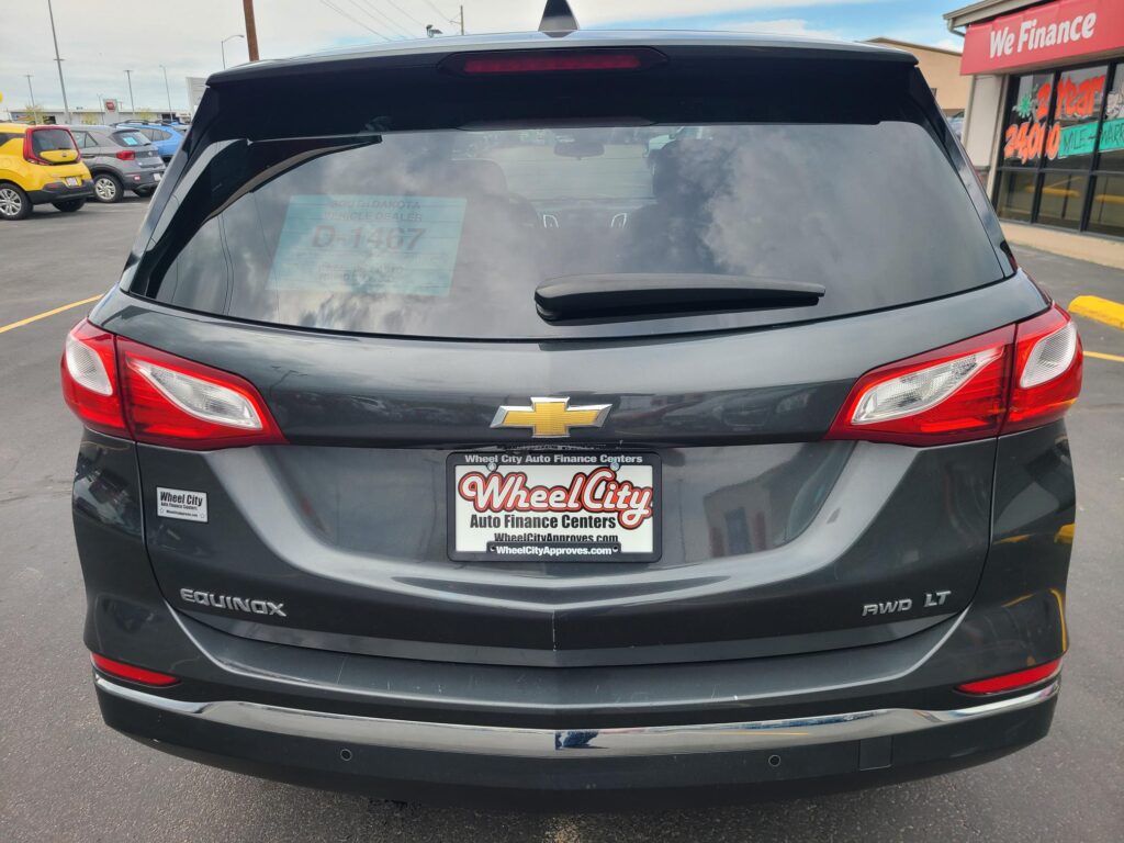Rear view of a dark Chevrolet Equinox SUV in a car dealership lot, with Wheel City Auto Finance license plate frame visible.