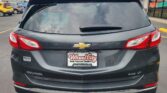 Rear view of a dark Chevrolet Equinox SUV in a car dealership lot, with Wheel City Auto Finance license plate frame visible.