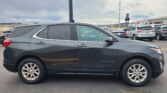 Side view of a dark gray Chevrolet Equinox parked in a car lot with other vehicles nearby under a cloudy sky? (informative image)