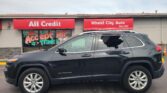 Front of All Credit/Wheel City Auto dealership with red awnings; gray SUV (Jeep Cherokee) parked in front, storefront graphics visible.
