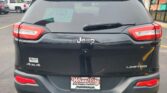 Rear view of a black Jeep SUV with 'LIMITED' and '4x4' badges, dealer plate reading Wheel City Auto Finance Centers, in a car lot.