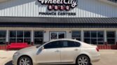 Beige four-door sedan parked in front of Wheel City Auto Finance Centers storefront with a red bench nearby.