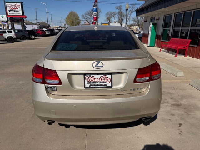 Beige Lexus sedan photographed from the rear in a car dealership lot, with a Wheel City Auto Finance Centers plate on the back.