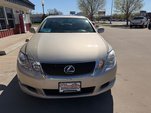 Front view of a beige Lexus sedan in a dealership parking lot, Wheel City license plate frame visible on the bumper.
