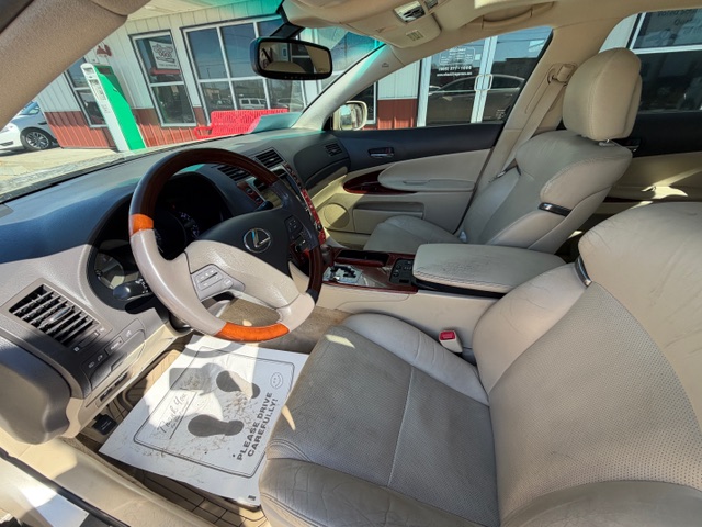 Front interior of a beige leather SUV, featuring a wood-trim steering wheel, center console, and front seats