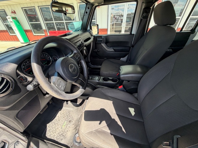 Interior view of a dark SUV showing the steering wheel, dashboard, and front seats with a center console between them.