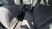Rear passenger area of a vehicle with gray cloth bench seat, three headrests, visible seat belts, and a cup holder on the floor between the front seats.