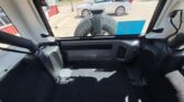 Cargo area with the hatch open; a mounted spare tire is visible through the rear window, along with a blue parking permit sticker on the glass, parked in a lot.