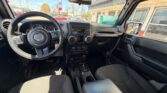 Interior view of a Jeep from the driver’s seat, showing steering wheel, center console, and dashboard gauges under bright daylight.