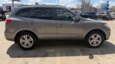 Side view of a gray mid-size SUV parked in a sunny parking lot, showing four doors, alloy wheels, and roof rails.