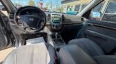 Interior view of a Hyundai sedan: steering wheel, dashboard, center console, and front seats with the driver's door open at a dealership area