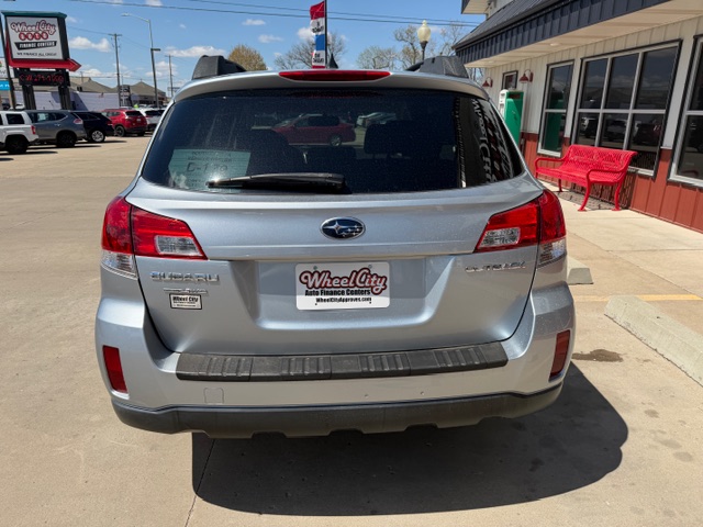 Rear view of a silver Subaru Forester in a dealership lot, Wheel City license plate frame and red benches nearby.