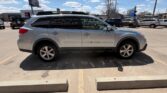 Silver crossover SUV photographed in a dealership lot, side view with roof rails and alloy wheels on a sunny day.