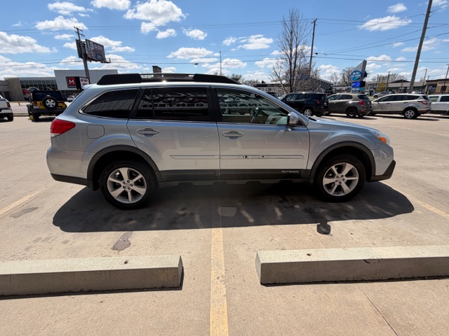 Silver crossover SUV photographed in a dealership lot, side view with roof rails and alloy wheels on a sunny day.