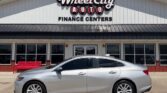 Silver 4-door sedan parked in front of Wheel City Auto Finance Centers storefront