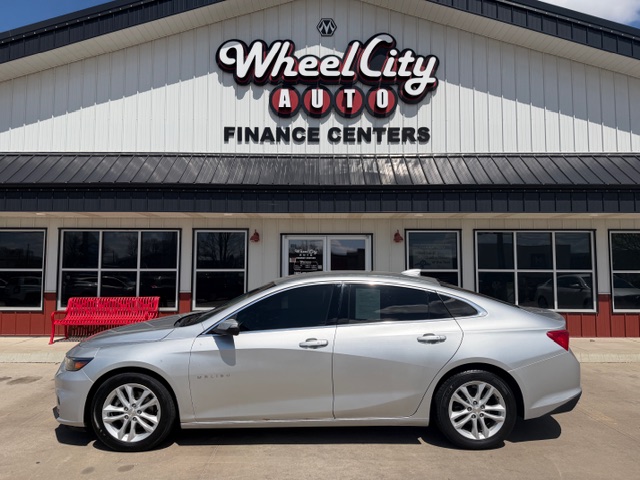 Silver 4-door sedan parked in front of Wheel City Auto Finance Centers storefront